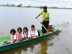 students in flooded area going to school by boat